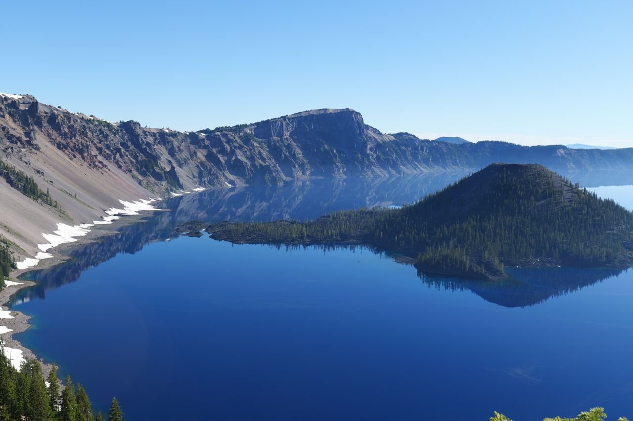 Aerial shot of Crater Lake National Park with clear blue water and surrounding cliffs