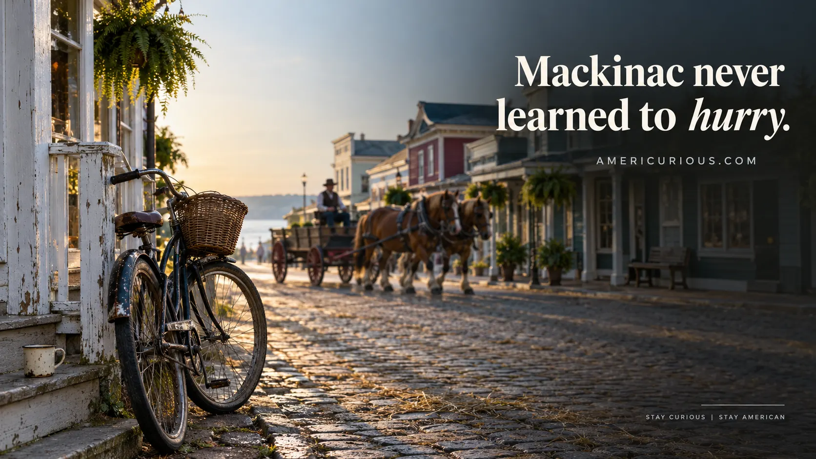 A worn black bicycle with a wicker basket leans against a peeling white clapboard porch on Mackinac Island, Michigan, as a horse-drawn dray passes on damp cobblestone behind it — a car-free American morning, from americurious.com, where we Stay Curious | Stay American.